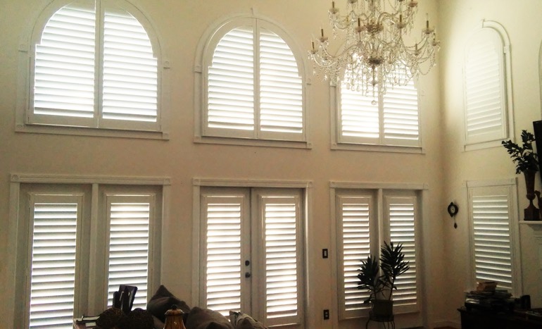 TV room in open concept New York house with plantation shutters on tall windows.