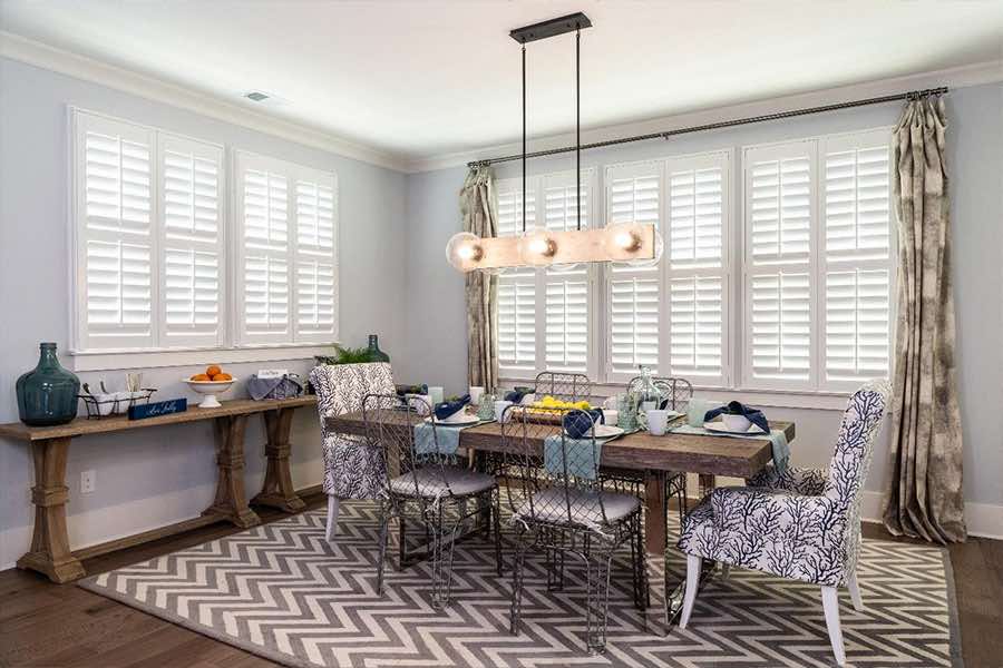 Elegant curtains layered over interior shutters distract from different-sized windows. Polywood shutters and curtains on dining room windows of different sizes
