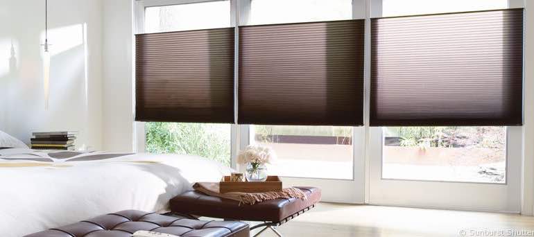 Minimal New York bedroom with high ceiling windows and brown cellular shades.