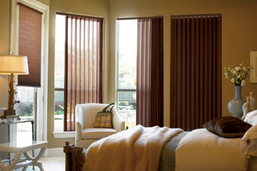 Choose durable and high-quality fabric or vinyl vertical blinds in New York. Maroon fabric vertical blinds inside a bedroom