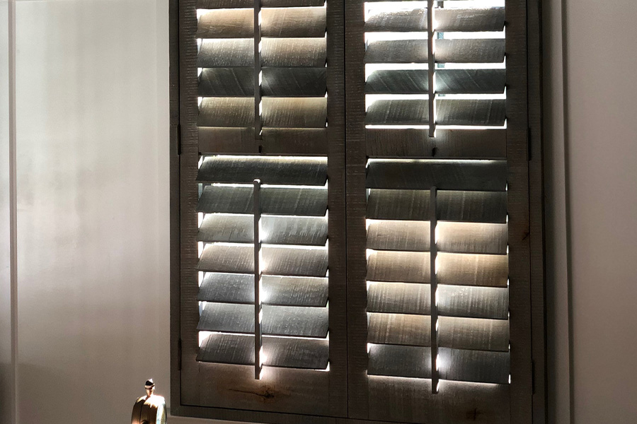 Always use a dry duster to maintain the life of reclaimed wood shutters. Reclaimed wood shutters in a bathroom.