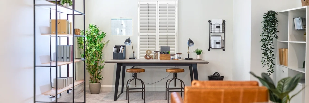White Polywood shutters on a window over a home office desk