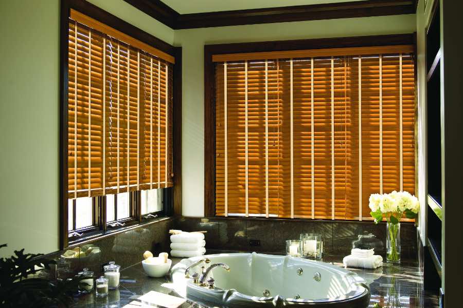 Premium quality blinds are always a stylish accent in your New York home. Brown wood blinds on large windows in a green bathroom