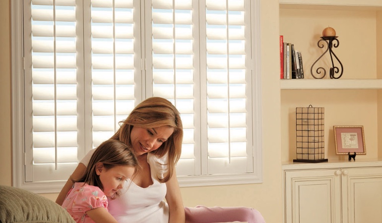 Easy to clean Polywood shutters are great cord-free options for kids. Mom and daughter in front of window