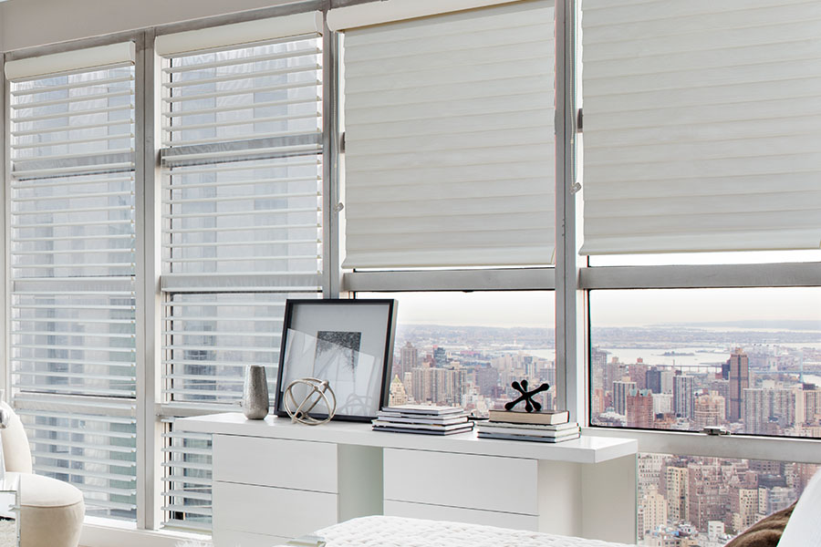 Sheer window shades let you enjoy some privacy and soft light. White sheer shades on a wall of windows in a white bedroom