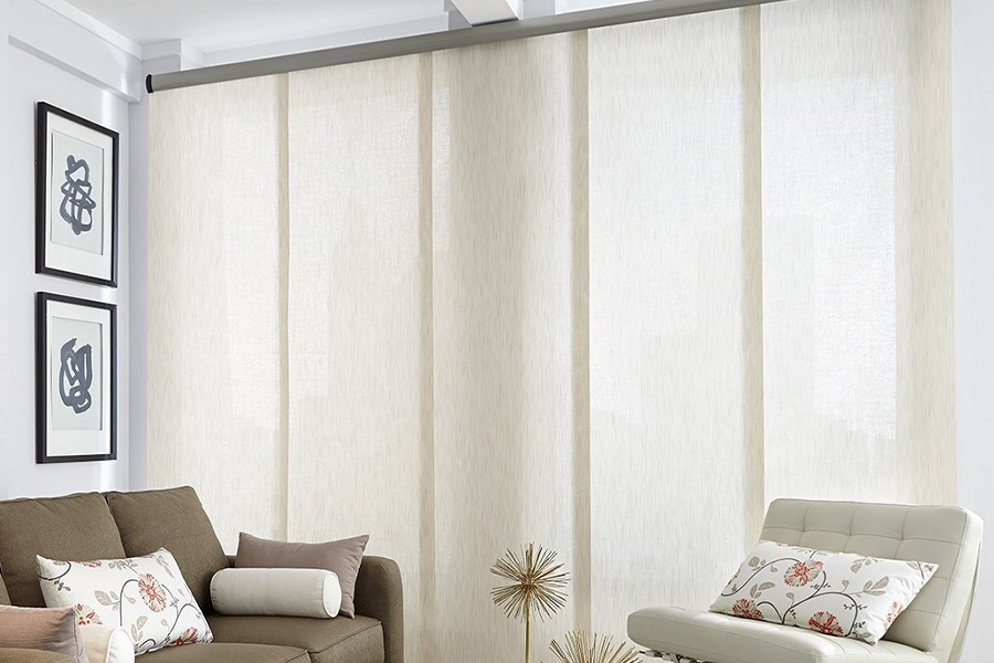 Find window treatments to complete any interior design among our extensive selection at Sunburst Shutters New York.  Long off-white window shades on a tall window in a modern living room