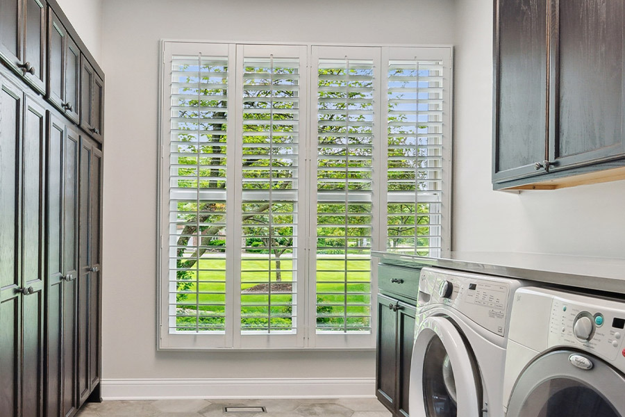 Find the perfect level of natural light for your New York laundry room with interior shutters. White Polywood shutters letting light through a laundry room window