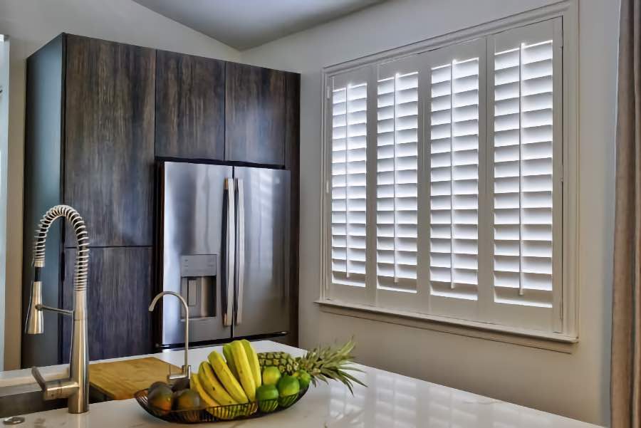 Homeowners use indoor window shutters in New York when they want attractive and functional window treatments. Polywood shutters on a large kitchen window