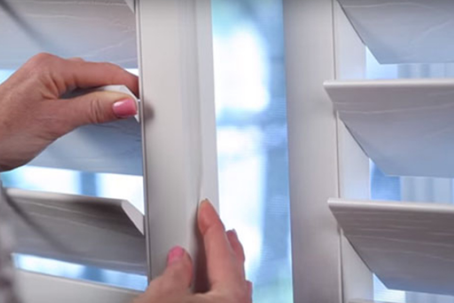 Close window gaps with DIY caulk and weatherstripping or invest in window products that come with weatherstripping. A woman's hands showing off weatherstripping on Polywood shutters on a window