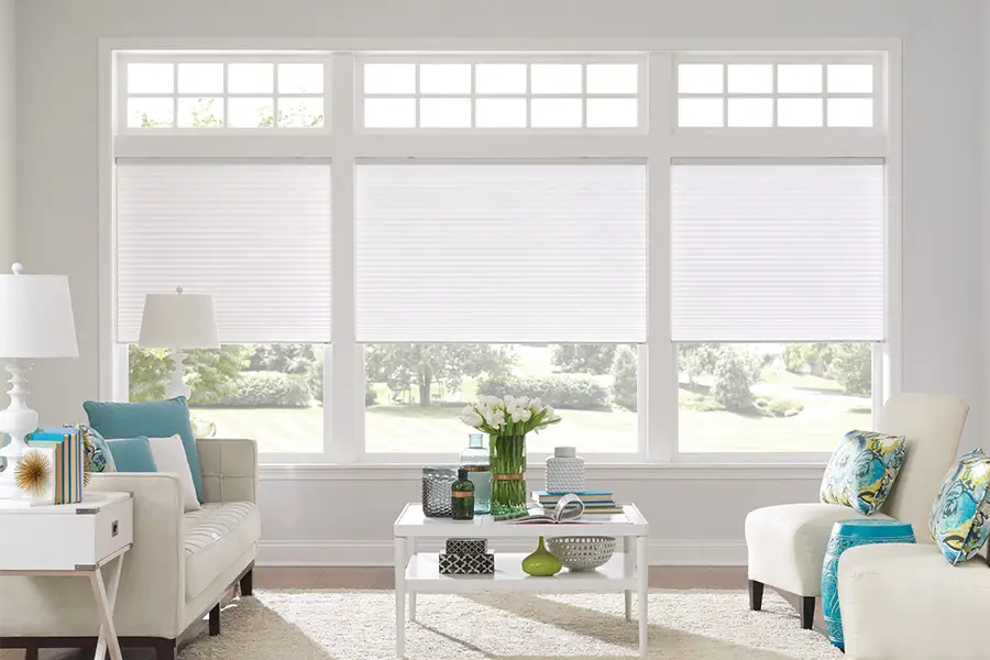 Insulating cellular shades can help keep cold air and hot UV rays from entering your New York home. White cellular shades on windows in a white living room